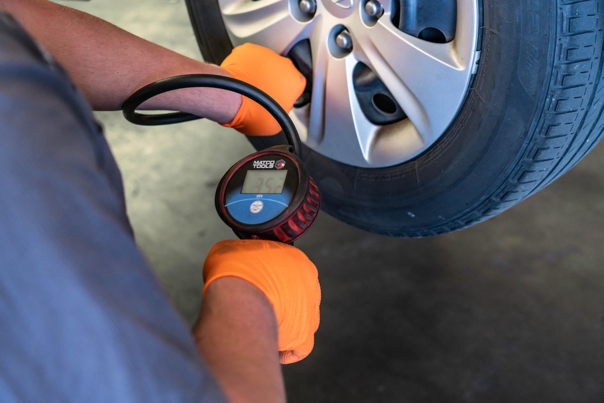 Technician checking tire pressure with a gauge